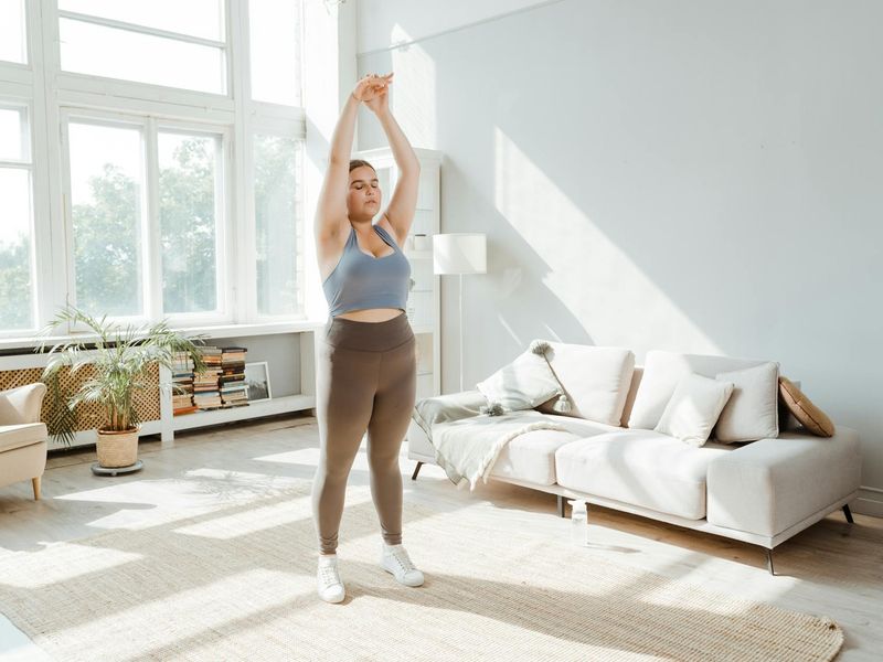 Person doing a stretching exercise in a bright, minimalist room.